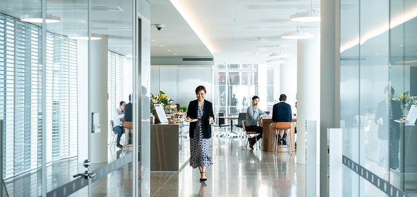 A colleague crossing the floor between glass partitions.
